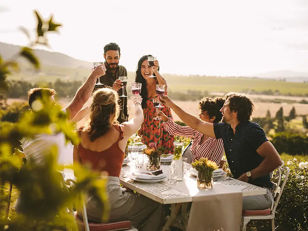 Gruppe von Freunden trinkt Rotwein vor einem Olivenhain